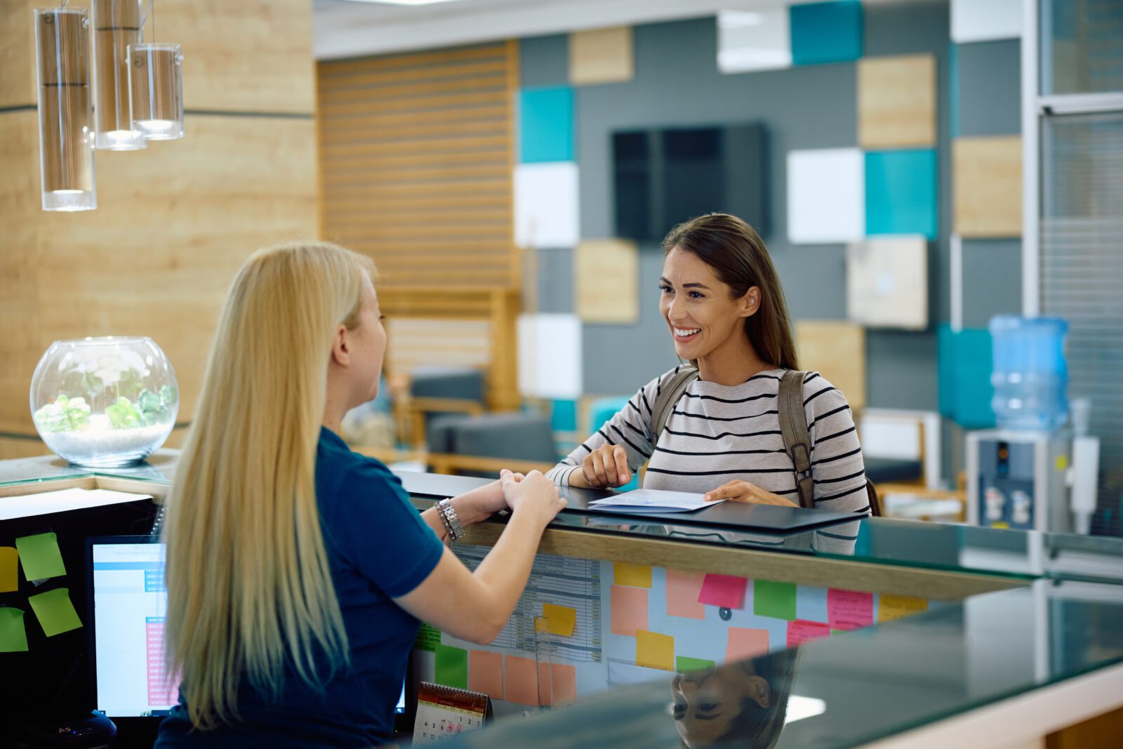 Happy woman talking to a nurse at reception desk at doctor’s office.